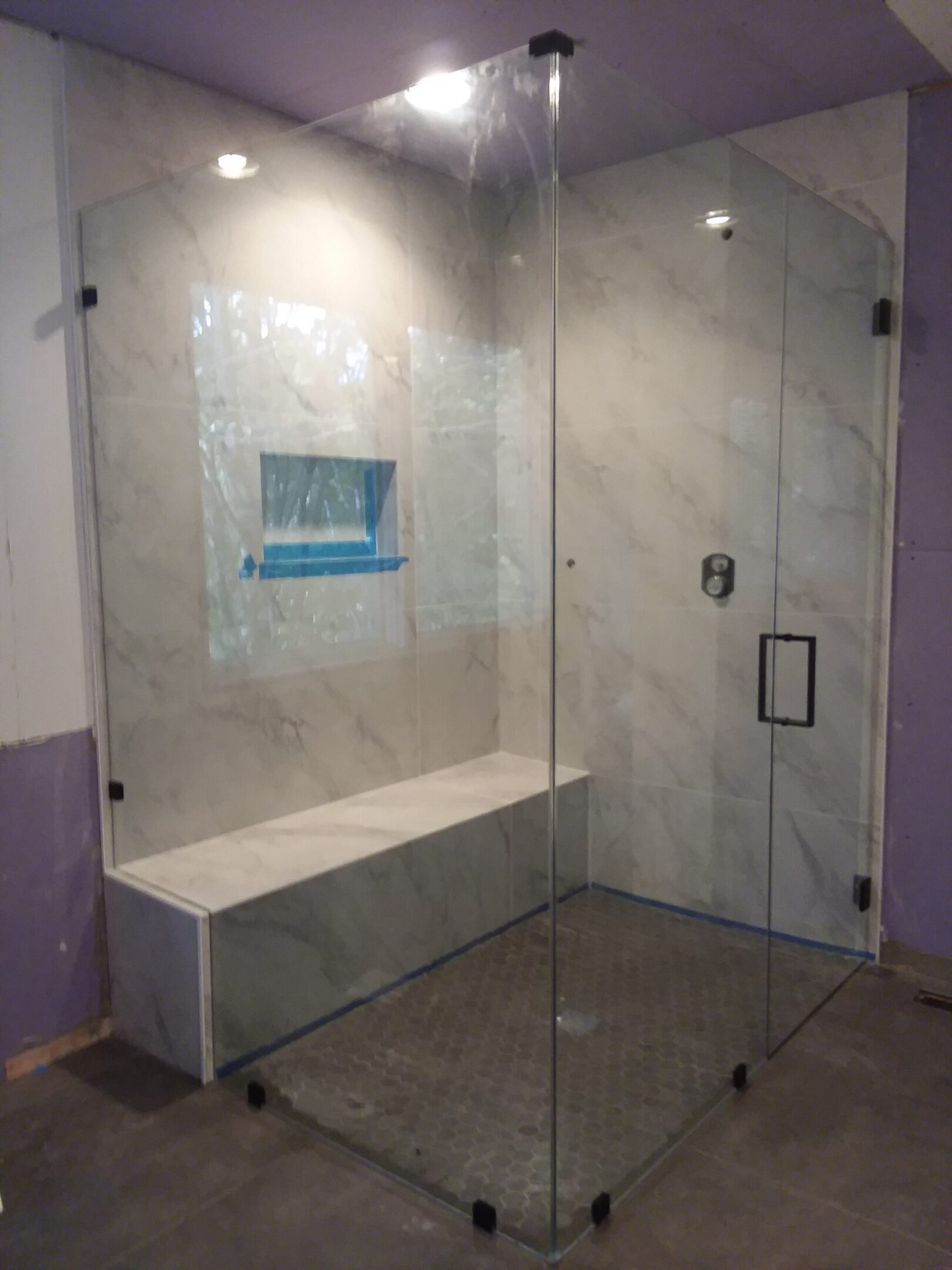 A shower with glass doors and a bench in the middle.