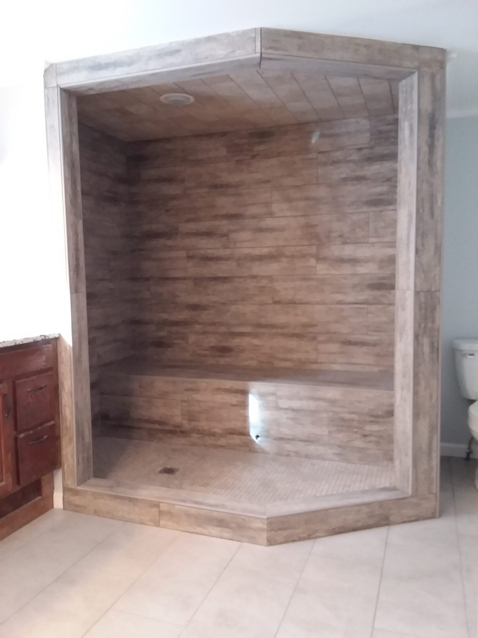 A wooden stall in the middle of a bathroom.