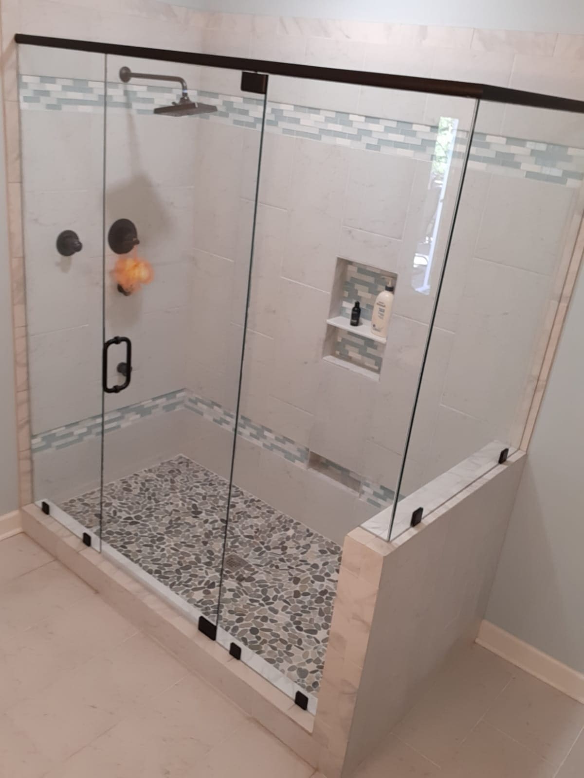 A bathroom with a glass shower door and tile floor.