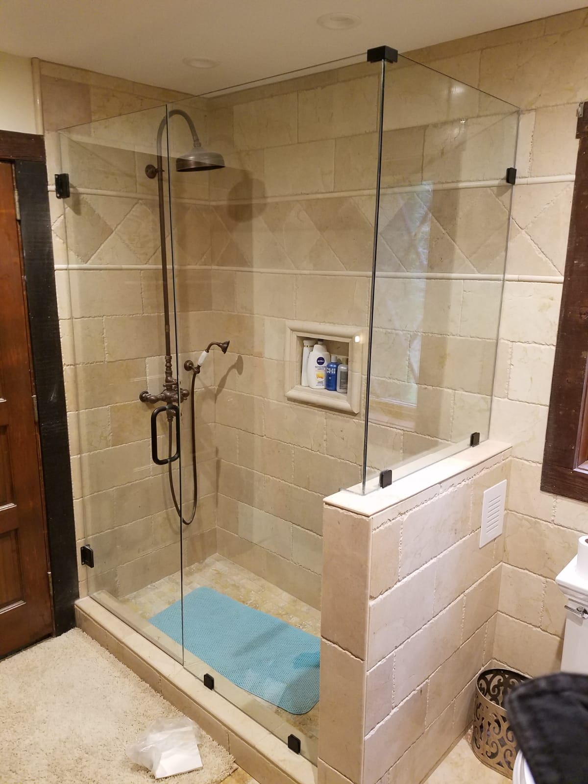 A bathroom with a glass shower door and tiled walls.