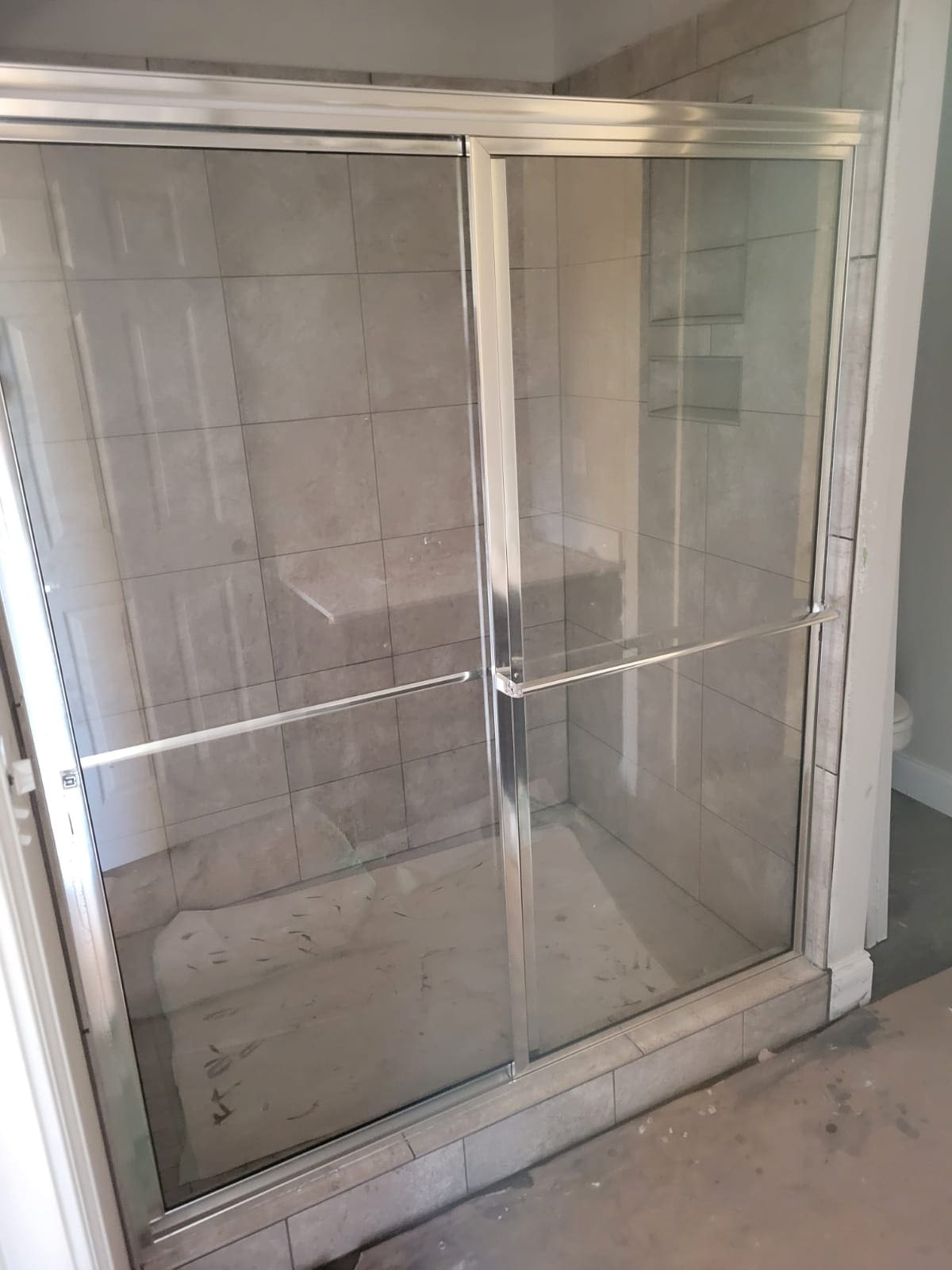 A glass door in the shower of a bathroom.