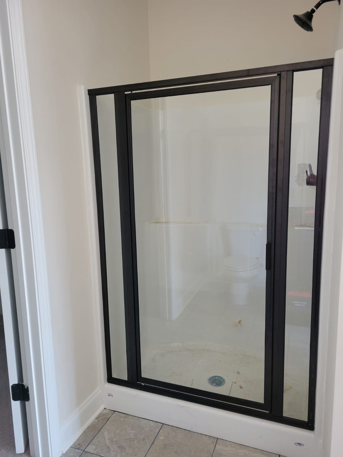 A bathroom with a shower door that has been opened.