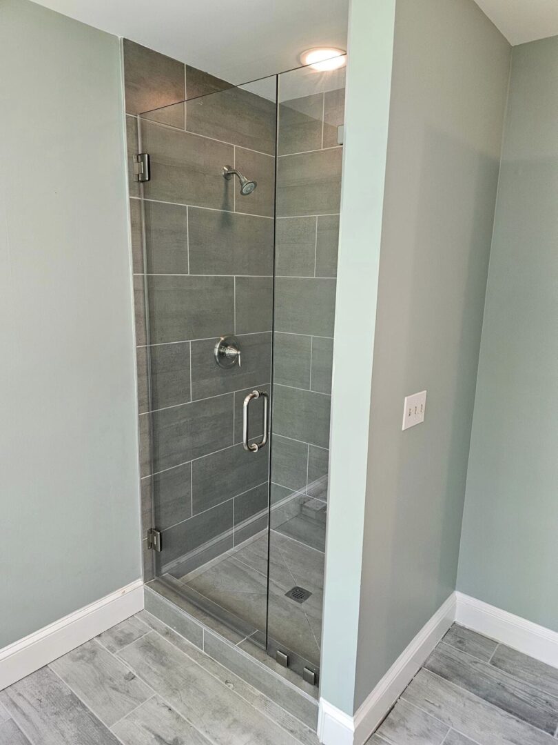 A bathroom with a glass shower door and tiled walls.