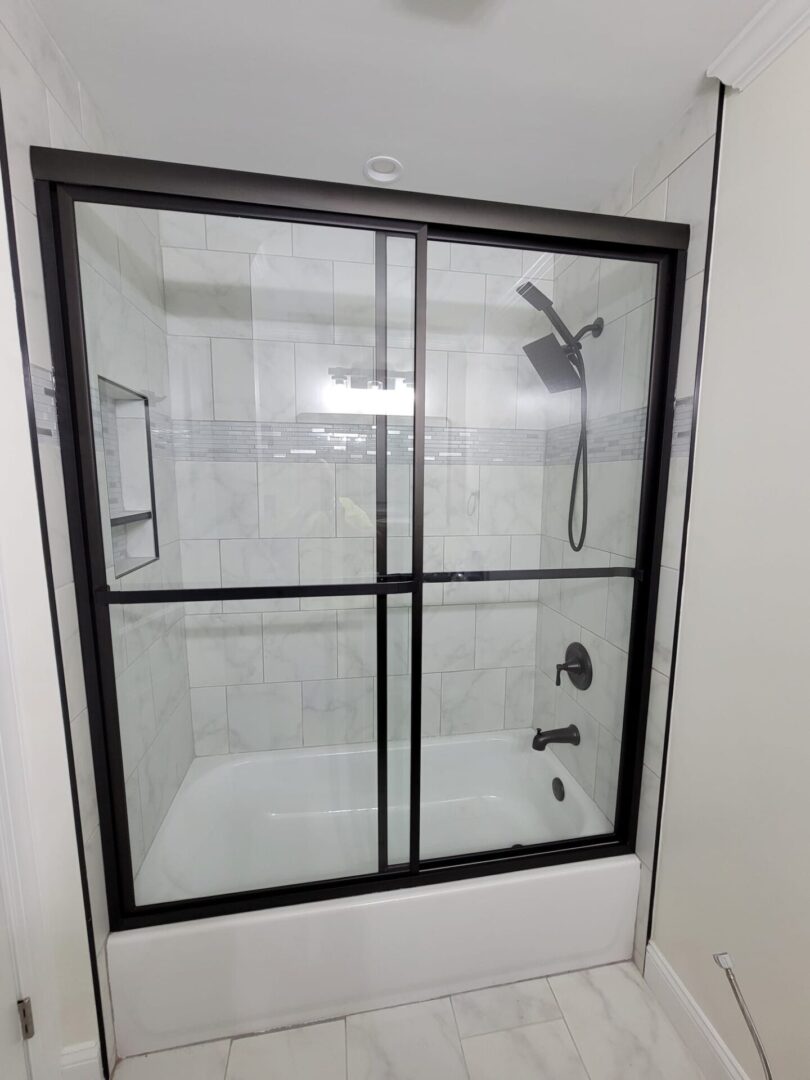 A shower with black trim and glass doors.